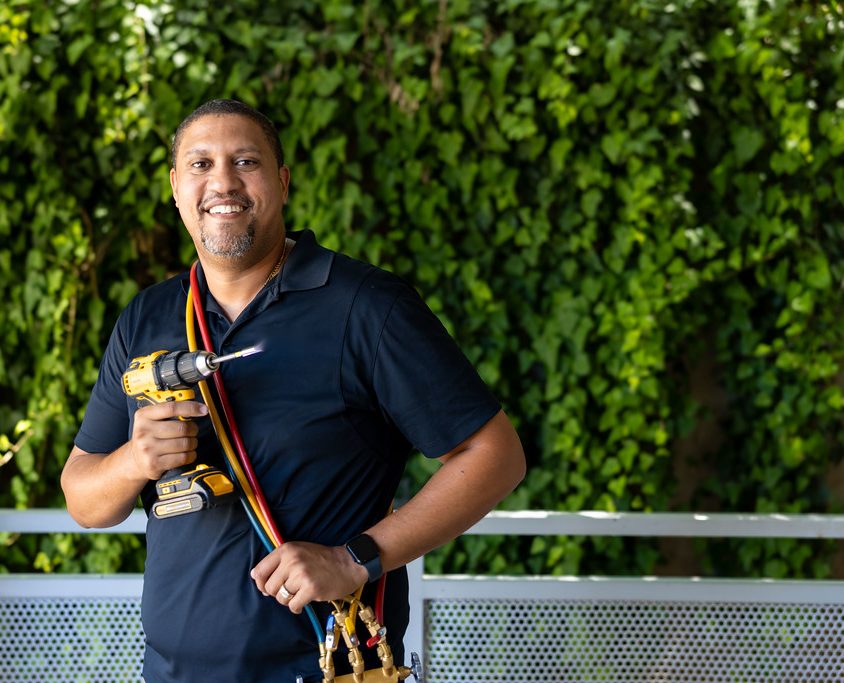 A smiling AC technician holding his tools